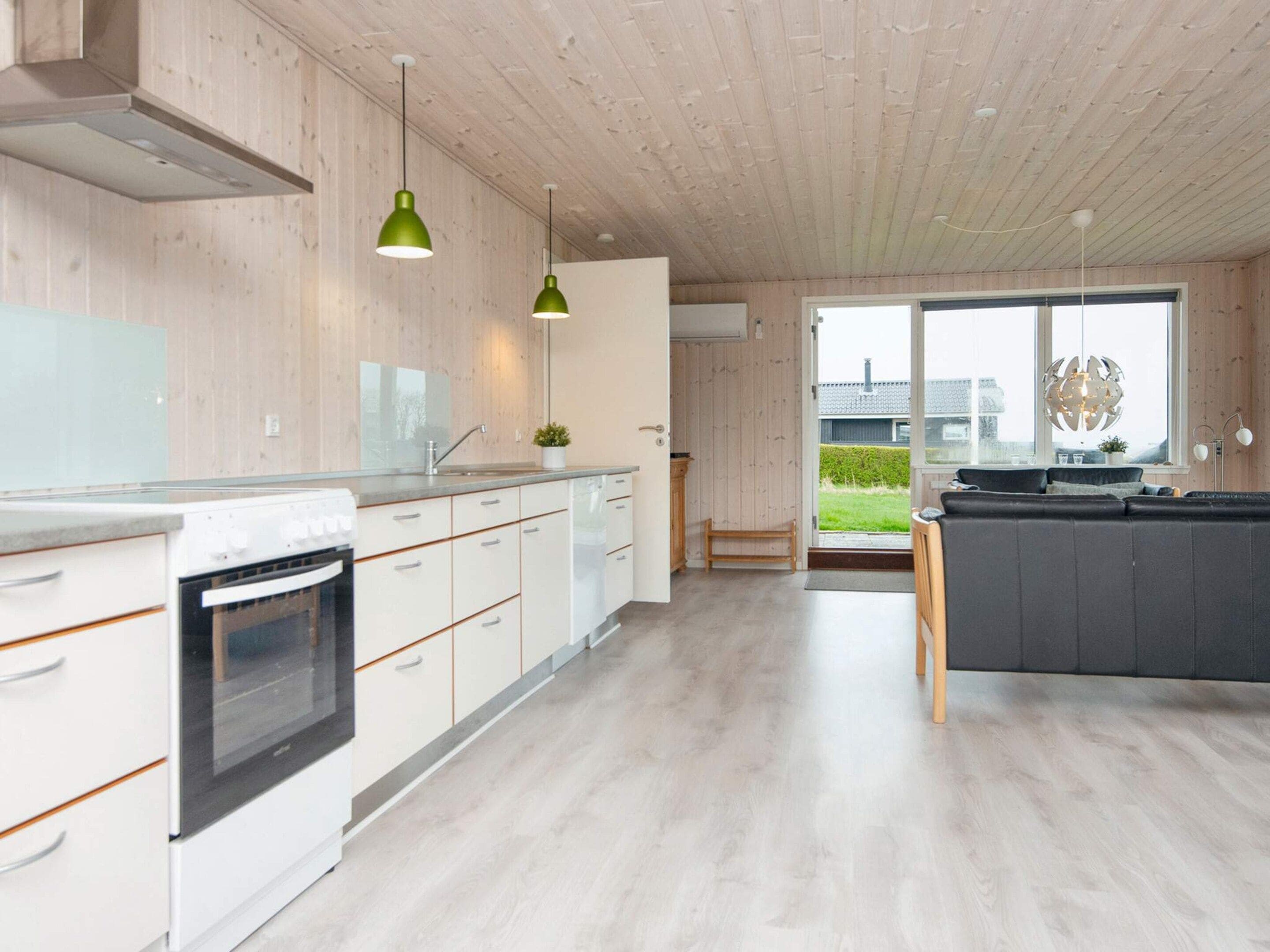Een moderne keuken met houten kasten, een inbouwoven en hanglampen.