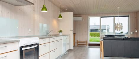 Een moderne keuken met houten kasten, een inbouwoven en hanglampen.