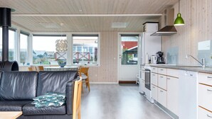 Une cuisine moderne avec des meubles blancs, un plan de travail noir et un luminaire suspendu vert.