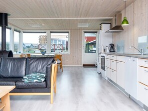 A modern kitchen with white cabinets, a black countertop, and a green pendant light. - 7 Person Holiday Home in Juelsminde (Horsens)