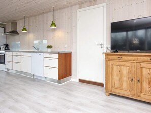 A modern kitchen with wooden cabinets, a built-in oven, a sink, and a television on a wooden cabinet. - 7 Person Holiday Home in Juelsminde (Horsens)