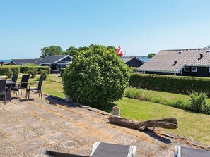 A residential area with houses, a flag, and outdoor furniture. - 7 Person Holiday Home in Juelsminde (Horsens)