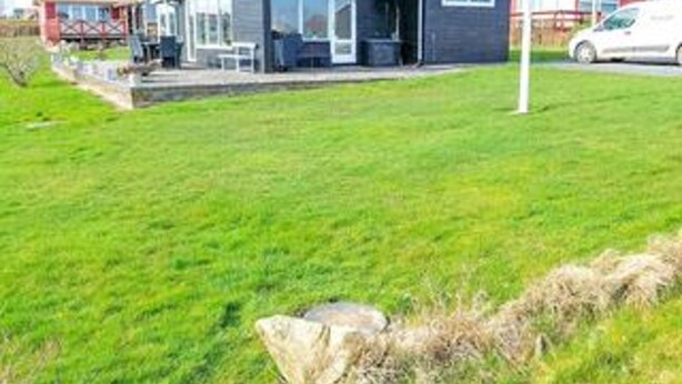 Une maison moderne avec une grande pelouse, un patio et une voiture garée à proximité.