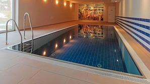 An indoor swimming pool with a tiled floor, a metal ladder, and a wall with a mural. - Beach Idyll Holiday Apartment (Ostseebad Baabe)