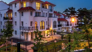 A multi-story hotel with a red-tiled roof, balconies, and a well-lit facade. - Beach Idyll Holiday Apartment (Ostseebad Baabe)