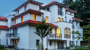 A multi-story building with balconies and large windows, surrounded by greenery. - Beach Idyll Holiday Apartment (Ostseebad Baabe)