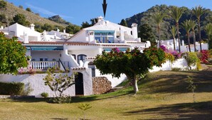 A white villa with a balcony, surrounded by lush greenery and palm trees. - La Perla - South Facing, Sun Morning to Evening (Nerja)
