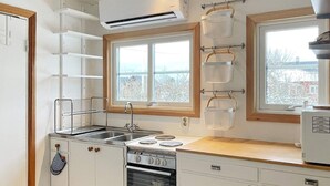 Eine kleine Küche mit Herd, Spüle und einem Fenster mit Blick.