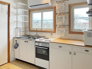 Cocina compacta con estufa, lavamanos y ventana con vistas.
