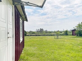 A red barn with a white door, a grassy field, and a stone wall in the background.