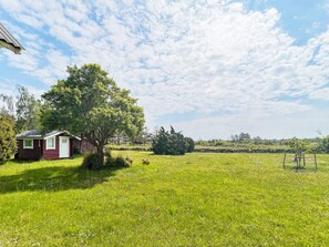 A rural property with a small red building, a large tree, and a grassy field.