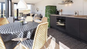 Ett modernt kök med matplats, med en stor köksö, mörka skåp och en grön accentvägg.
