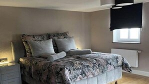 Un dormitorio con una cama, una mesita de noche, una ventana y un radiador.