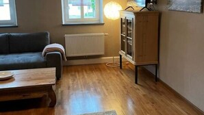 Una sala de estar con un sofá, una mesa de centro de madera, un mueble aparador y un radiador.