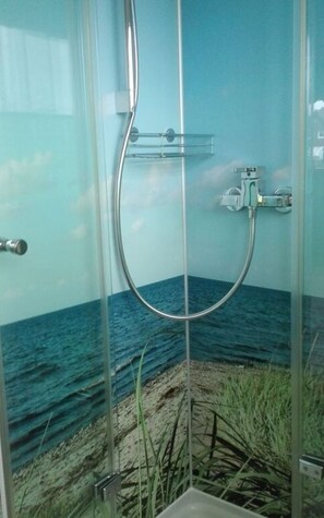 A glass-enclosed shower with a view of the ocean and beach. - Holiday Apartment Grohnert (Lübeck)