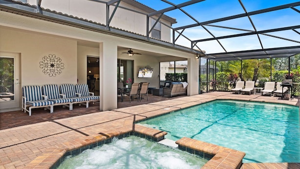 A covered outdoor swimming pool with lounge chairs and a hot tub area.