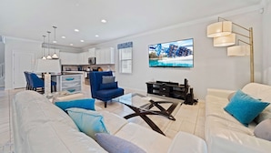 A modern living room with a white sofa, a blue armchair, and a glass coffee table.