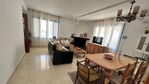 A spacious living room with a sofa, TV, dining table, and chairs. - Belvilla by OYO Casa Manuela (Roquetas de Mar)