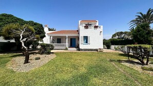 A white building with a red-tiled roof, a balcony with flowers, and a well-maintained lawn. - Belvilla by OYO Casa Manuela (Roquetas de Mar)