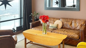 Een woonkamer met een leren bank, een houten salontafel en een vaas met rode bloemen.