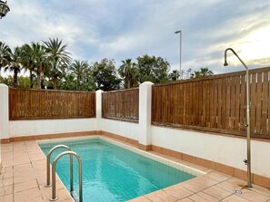 A rectangular pool with a wooden fence and a metal handrail.