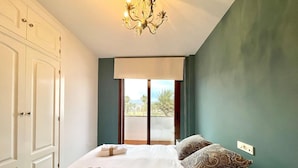 Un dormitorio con cama, candelabro, armario y vistas por la ventana.