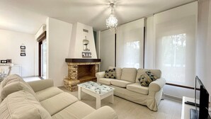 Una sala de estar con chimenea, un conjunto de sofás, una mesa de centro y un televisor.
