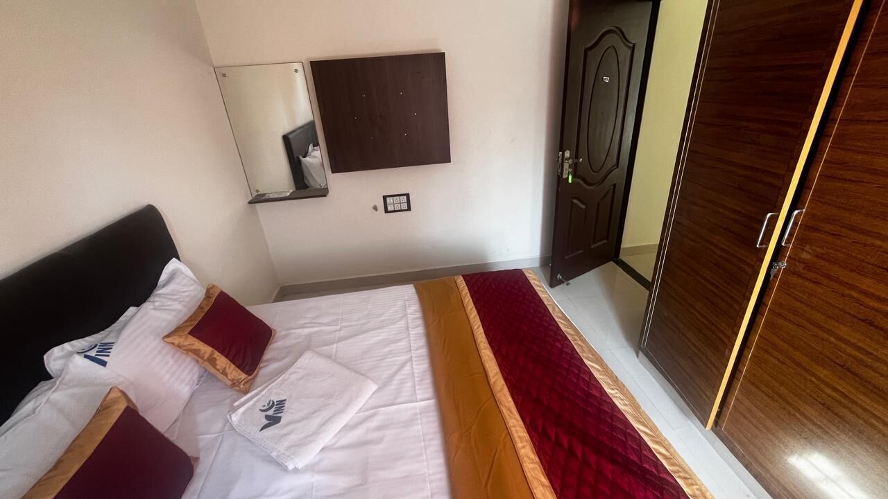 A bedroom with a bed, a wardrobe, a mirror, and a door.
