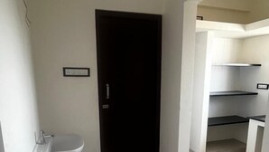 A hallway with a black door, a white sink, and a tiled floor.