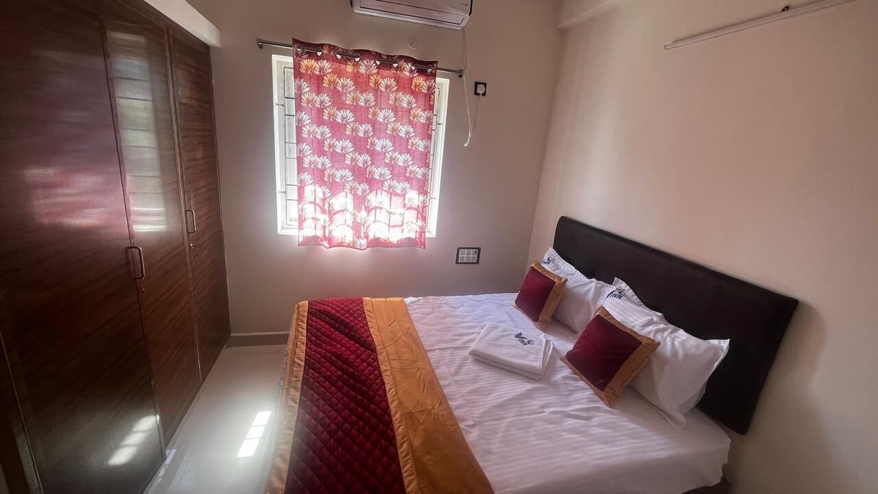 Un dormitorio con cama, ventana con cortina, armario y aire acondicionado instalado en la pared.