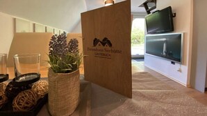 A reception area with a wooden sign, a potted plant, and a television on the wall. - Holiday Home Seehutte (Malschwitz)