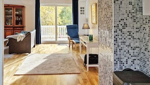 Una sala de estar con piso de madera, un sofá, una mesa de centro, una chimenea y vistas al exterior.