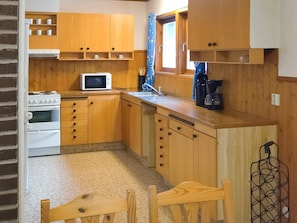 A compact kitchen with wooden cabinets, a microwave, a stove, and a coffee maker. - 6 Person Holiday Home in Ed (Ed)