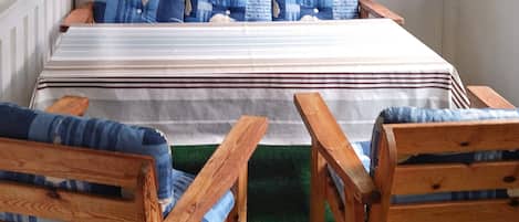 Une chambre à coucher avec un lit, deux chaises en bois, une fenêtre donnant sur une pelouse et une moquette verte.