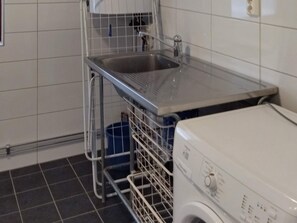 A laundry area with a washing machine, a sink, and a metal rack. - 6 Person Holiday Home in Ed (Ed)