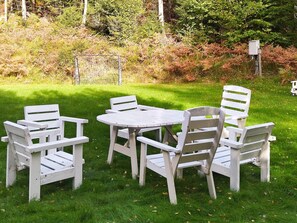 Un ensemble de mobilier d’extérieur blanc, composé d’une table ronde et de six chaises, disposé sur une pelouse verdoyante.