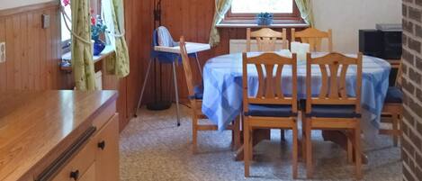 A room with a wooden table and chairs, a small window with curtains, and a radiator.