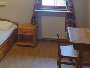 A small room with a bed, a wooden nightstand, a table, and a chair. - 6 Person Holiday Home in Ed (Ed)