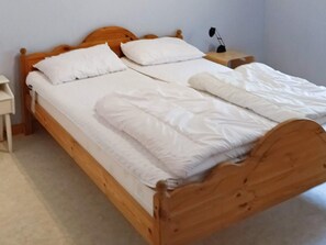 A single bed with a wooden frame, white bedding, and a bedside table with a lamp. - 6 Person Holiday Home in Ed (Ed)