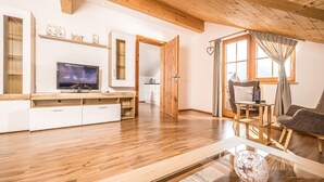 A modern living room with wooden flooring, a TV, a sofa, and a dining area. - Chalet in Reith Near Ski Juwel Alpbachtal (Reith im Alpbachtal)