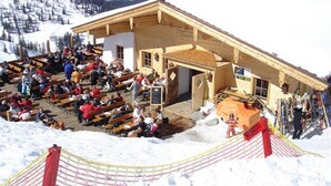 A wooden building with a sloped roof, benches, and a ski slope in the background. - Chalet in Reith Near Ski Juwel Alpbachtal (Reith im Alpbachtal)