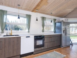 Una cocina moderna con horno empotrado, refrigerador de acero inoxidable y una ventana con cortinas.