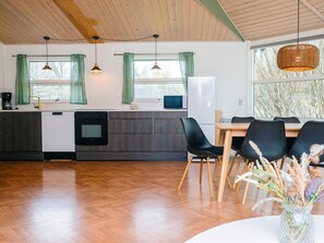 A modern kitchen with a dishwasher, oven, and microwave. There is a dining area with a table and chairs. - 4 Star Holiday Home in Ansager (Ansager)