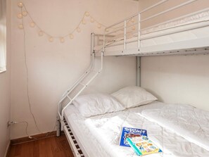 Una cama litera con escalera, una almohada blanca y un libro titulado 'Super Charlie' en la litera inferior.