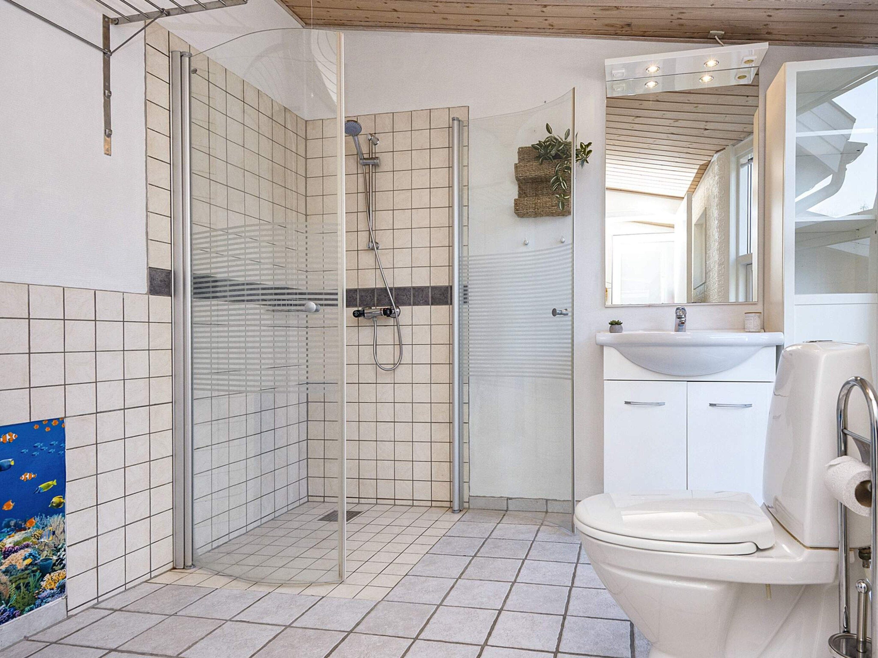 A bathroom with a glass-enclosed shower, a sink, and a toilet.