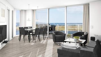Una sala de estar moderna con comedor, ventanas amplias y vista al mar.