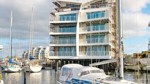 A multi-story building with balconies, a marina with boats, and construction equipment. - 5 Star Holiday Home in Wendtorf (Wendtorf)