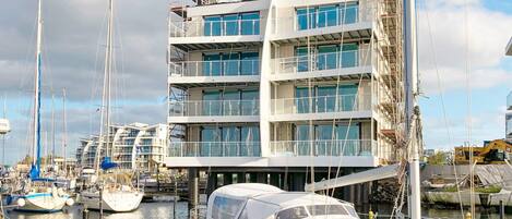Un immeuble à plusieurs étages doté de balcons, une marina avec des bateaux et du matériel de construction.