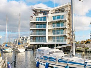 A multi-story building with balconies, a marina with boats, and construction equipment. - 5 Star Holiday Home in Wendtorf (Wendtorf)