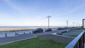 A coastal road with parked cars, a grassy area, and a clear view of the beach. - Attractive Studio With a Sea-view (Middelkerke)